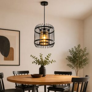 Black cage pendant light with glass shade installed above a dining table.