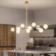 Modern gold 14-light linear chandelier with milk-white glass globe shades and G9 bulb holders.