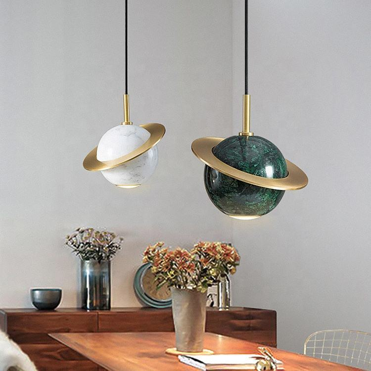 Planet marble glass ball pendant light with gold ring accents in cream and black finishes.